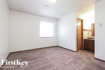 Indianapolis house for rent - the living room of a small white house with carpet and a window