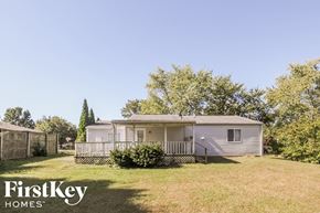 Indianapolis house for rent - a small white mobile home in a backyard with a yard and trees