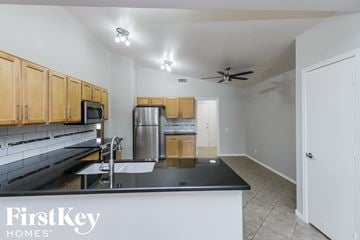 Mesa house for rent - A kitchen with a black counter top and wooden cabinets.