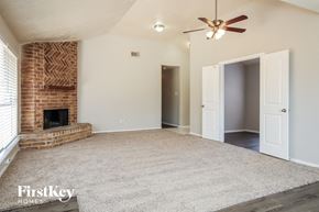 Humble house for rent - an empty living room with a brick fireplace and a ceiling fan