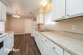 Humble house for rent - a kitchen with white cabinets and a counter top and a sink