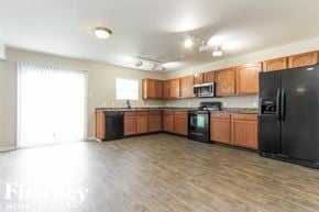 Camby house for rent - an empty kitchen with wooden cabinets and black appliances