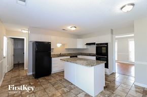 Cordova house for rent - a kitchen with white cabinets and a black refrigerator