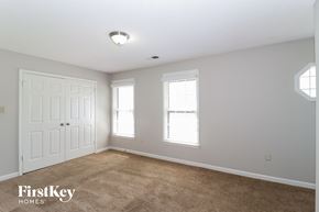 Cordova house for rent - a bedroom with a carpeted floor and two windows and a white door