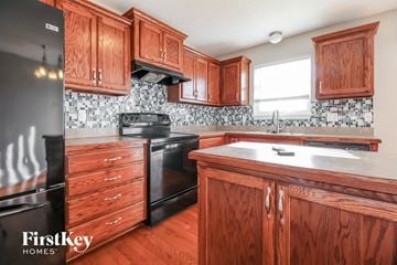 Kansas City house for rent - A kitchen with wooden cabinets and a black fridge.