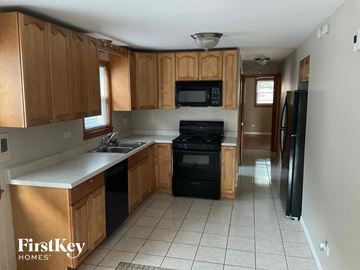 Chicago house for rent - an empty kitchen with wooden cabinets and black appliances