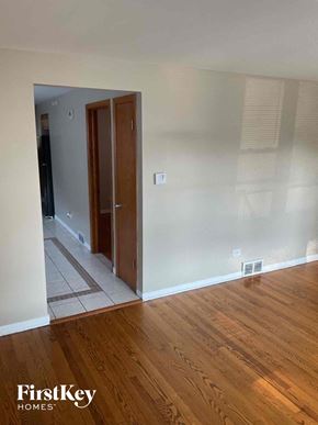 Chicago house for rent - an empty living room with wooden floors and a door to a hallway