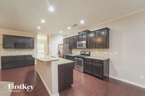 Charlotte house for rent - a kitchen with black cabinets and white counter tops and a wooden floor