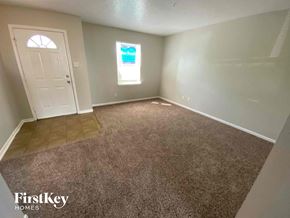 Camby house for rent - an empty living room with gray carpet and a white door