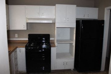 Kansas City house for rent - A black refrigerator sits next to a black stove in a kitchen.