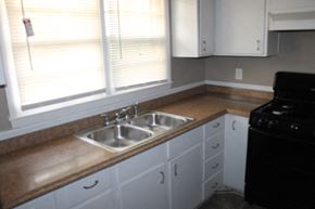 Kansas City house for rent - A kitchen with a black stove and a sink with a brown counter top.