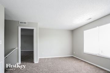 Indianapolis house for rent - the living room of an apartment with carpet and a door to the hallway