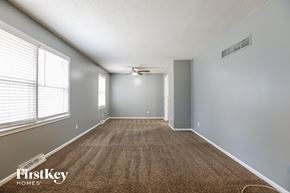 Kansas City house for rent - an empty living room with carpet and a ceiling fan