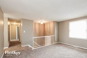 Indianapolis house for rent - A spacious room with a carpeted floor and a window with white blinds.