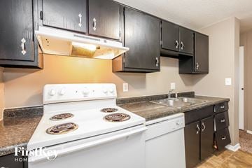 Indianapolis house for rent - A kitchen with black cabinets and a white stove top oven.