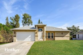 Fort Myers house for rent - a beige house with a garage door and a lawn