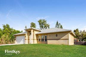 Fort Myers house for rent - a yellow house with a green lawn and trees