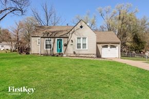 Kansas City house for rent - a white house with a green front yard and a white garage