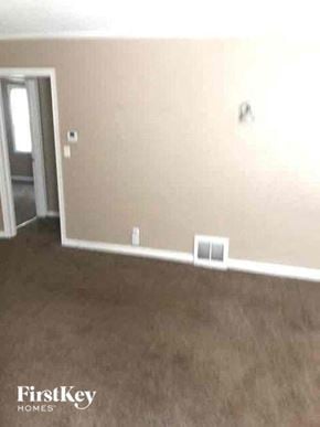 Kansas City house for rent - an empty living room with a brown carpet and a door