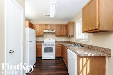 Fort Worth house for rent - a kitchen with wooden cabinets and a white stove and refrigerator