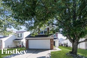 Indianapolis house for rent - A tree stands in front of a house with a garage.