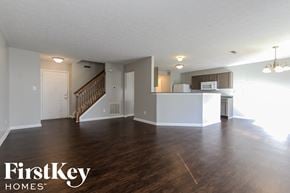Indianapolis house for rent - A spacious living room with wood flooring and a kitchen in the background.
