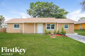 Fort Myers house for rent - a beige house with a lawn and a white door