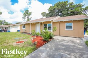 Fort Myers house for rent - a small tan house with a driveway and grass