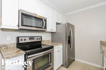 Fort Myers house for rent - a kitchen with stainless steel appliances and white cabinets