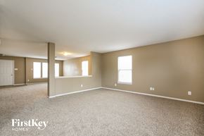 Pendleton house for rent - A spacious empty room with a carpeted floor and a white door on the left.