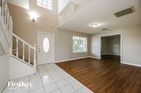 Fort Myers house for rent - an empty living room with a staircase and a white door