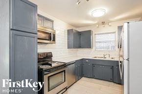 Texas City house for rent - a kitchen with navy blue cabinets and white appliances and a sink