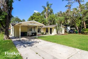 Tampa house for rent - a small yellow house with a yard and a driveway