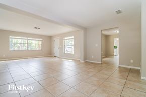 Tampa house for rent - an empty living room with tiled flooring and a door to the kitchen