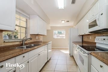 Tampa house for rent - a kitchen with white cabinets and white appliances and a sink