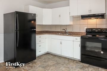 Kansas City house for rent - a kitchen with white cabinets and a black refrigerator