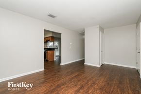 Tampa house for rent - A room with wooden floors and white walls, with a kitchen area visible through a doorway.