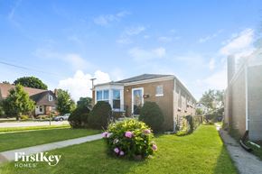 Evergreen Park house for rent - a brick house with a lawn and flowers in front of it