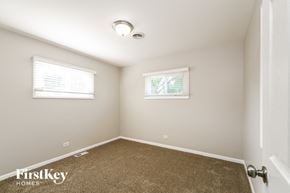 Evergreen Park house for rent - a bedroom with a carpeted floor and two windows