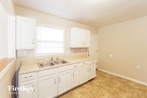 Kansas City house for rent - a kitchen with white cabinets and a sink and a window