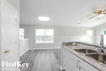 Charlotte house for rent - a kitchen with white cabinets and a sink and a ceiling fan