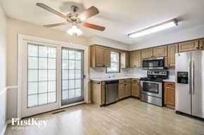 Overland Park house for rent - a kitchen with wooden cabinets and stainless steel appliances and a ceiling fan
