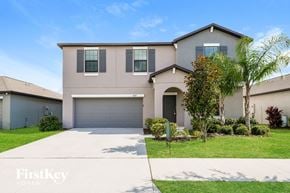 Ruskin house for rent - a beige house with a garage door and a lawn