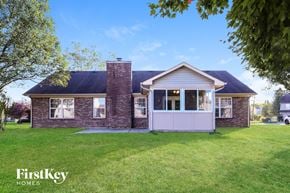 Indianapolis house for rent - A house with a brick chimney and a white door is surrounded by a grassy lawn.