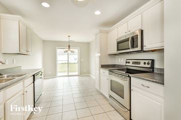 Avon house for rent - A kitchen with white cabinets and appliances, a chandelier, and a large window.