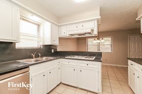 Spring house for rent - a kitchen with white cabinets and black counter tops