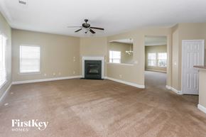 Charlotte house for rent - A spacious living room with a fireplace and a ceiling fan.