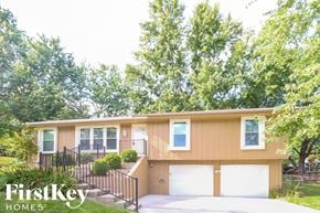 Kansas City house for rent - a yellow house with two garage doors and a driveway