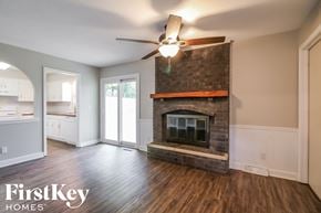 Kansas City house for rent - an empty living room with a fireplace and a ceiling fan