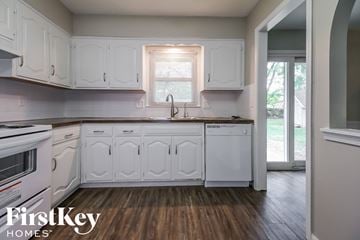 Kansas City house for rent - a kitchen with white cabinets and a sink and a window